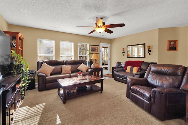 carpeted living room featuring ceiling fan and a textured ceiling