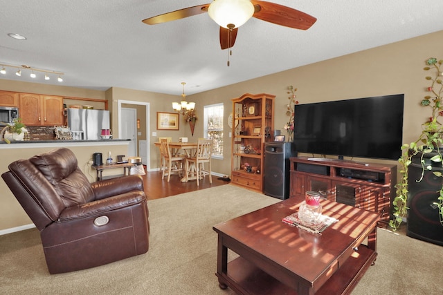 living room with ceiling fan with notable chandelier and a textured ceiling