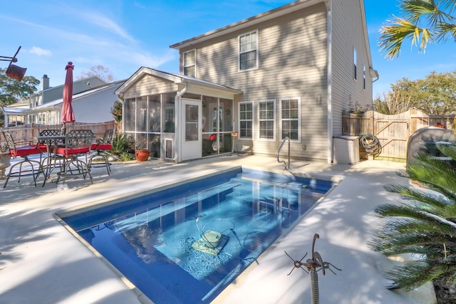 rear view of property featuring a fenced in pool, a patio area, and a sunroom