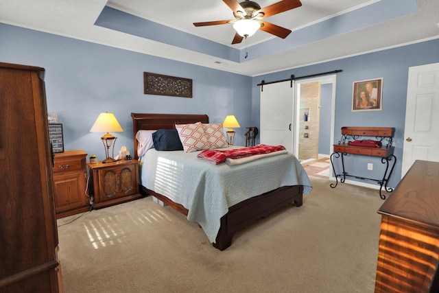 bedroom with a barn door, light colored carpet, a tray ceiling, and crown molding