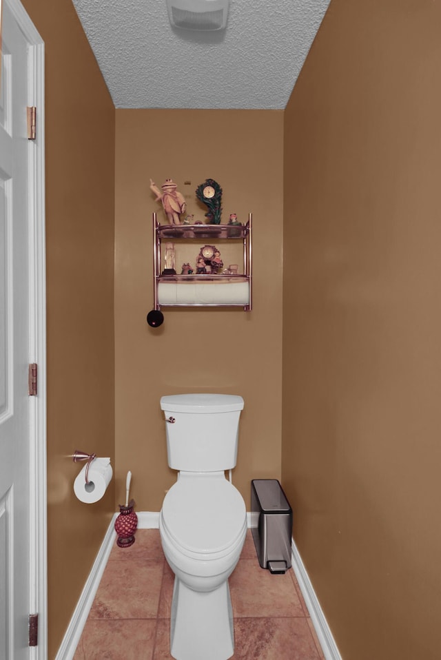 bathroom featuring a textured ceiling, tile patterned floors, and toilet