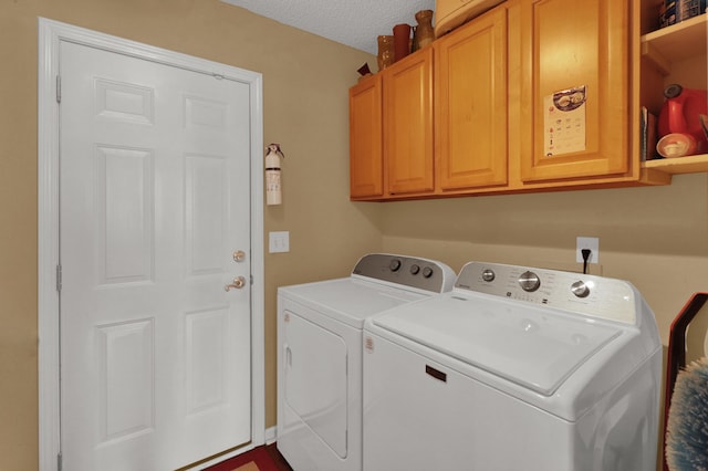 clothes washing area with cabinets, washing machine and dryer, and a textured ceiling