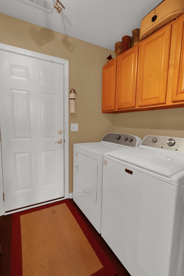 laundry area featuring cabinets, washing machine and clothes dryer, and a textured ceiling