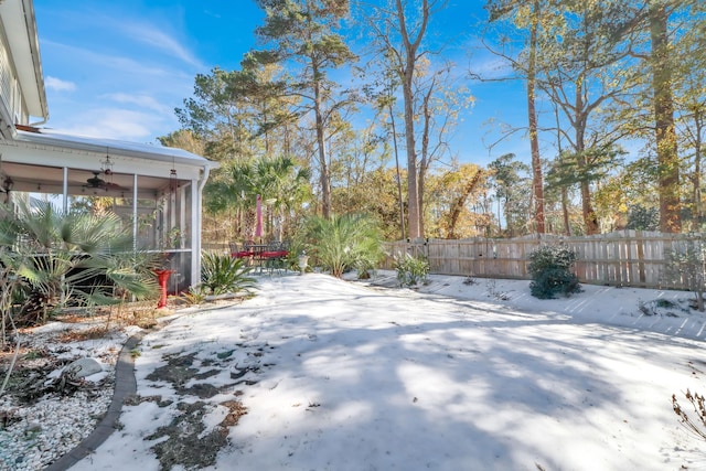 snowy yard with ceiling fan, a sunroom, and a patio area