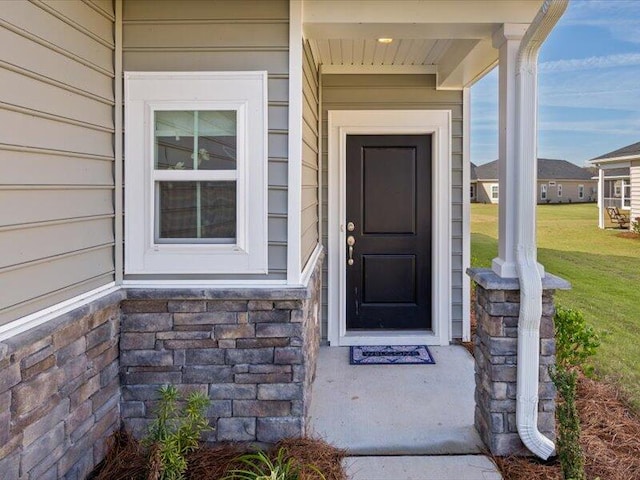 view of exterior entry with a yard