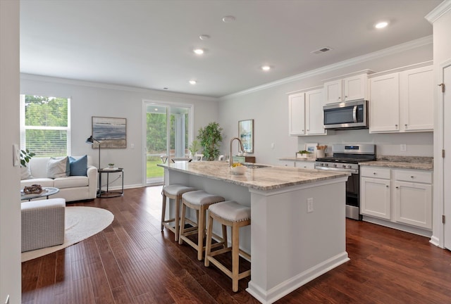 kitchen featuring dark hardwood / wood-style flooring, stainless steel appliances, sink, white cabinetry, and an island with sink