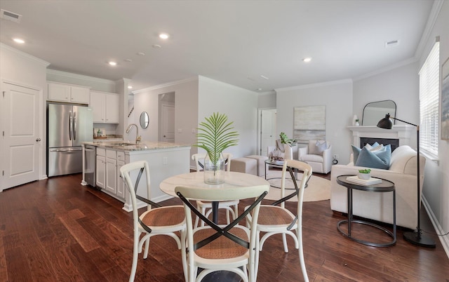 dining area with ornamental molding, dark wood-type flooring, and sink