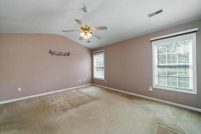 carpeted empty room with lofted ceiling, ceiling fan, visible vents, and baseboards