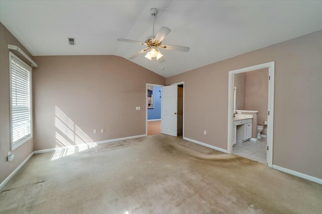 unfurnished bedroom with light colored carpet, lofted ceiling, visible vents, and baseboards