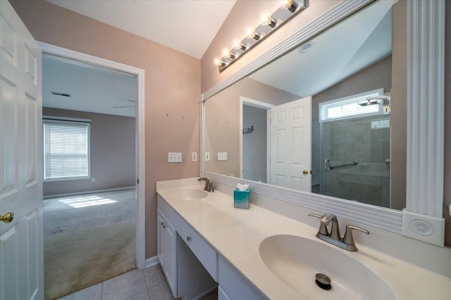 bathroom with vaulted ceiling, tiled shower, a sink, and tile patterned floors