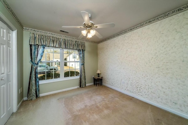 spare room featuring carpet floors, visible vents, a ceiling fan, baseboards, and wallpapered walls