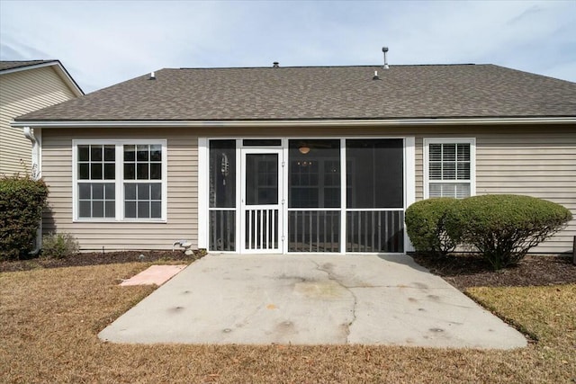 rear view of property featuring a shingled roof, a sunroom, and a patio area