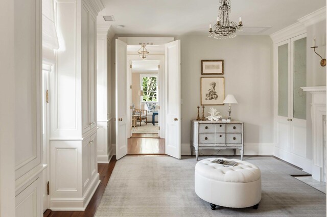 12 Orange St, Charleston, SC 29401 - living area featuring crown molding, visible vents, a decorative wall, a chandelier, and dark wood-style floors