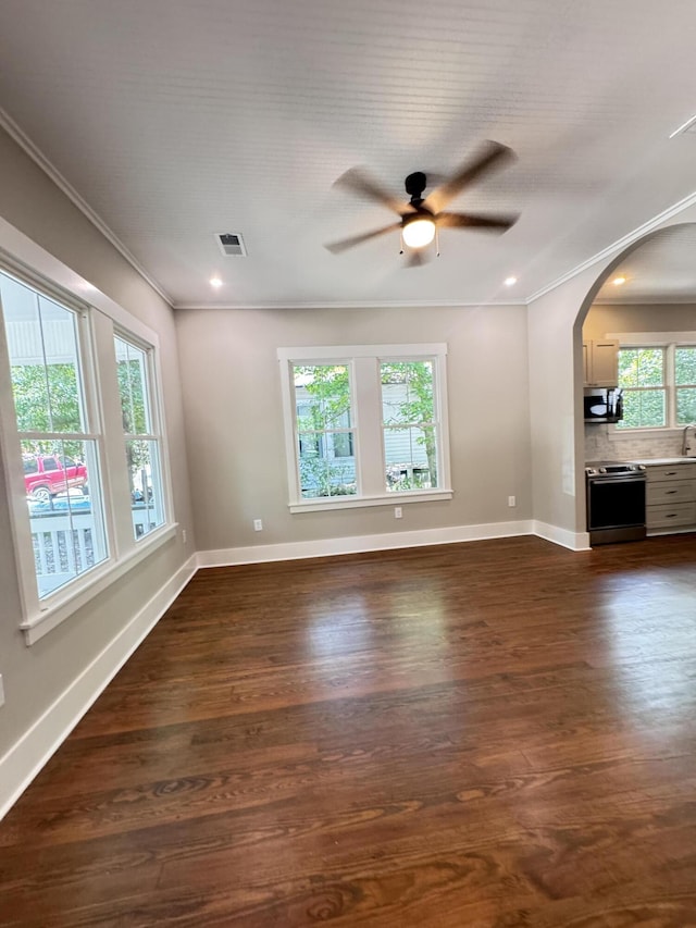 unfurnished living room featuring crown molding, a ceiling fan, dark wood finished floors, and baseboards