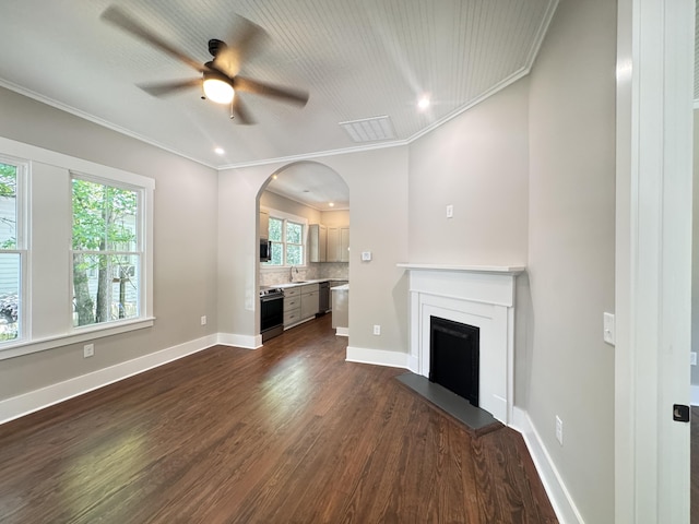 unfurnished living room featuring plenty of natural light, a fireplace with raised hearth, dark wood-style flooring, and ceiling fan