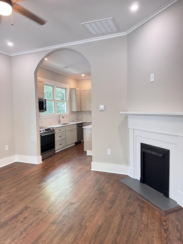 unfurnished living room with crown molding, dark wood-style flooring, a ceiling fan, and a sink