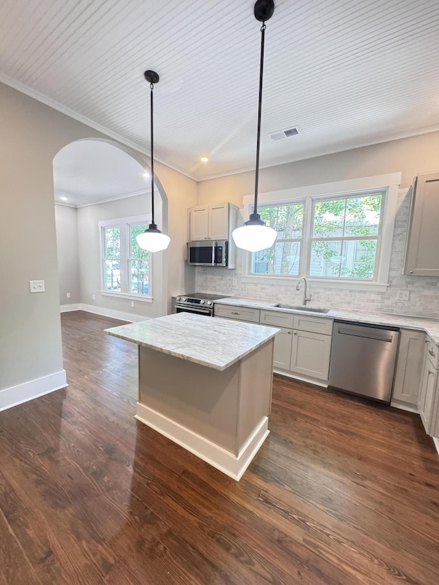 kitchen featuring stainless steel appliances, arched walkways, visible vents, and decorative backsplash