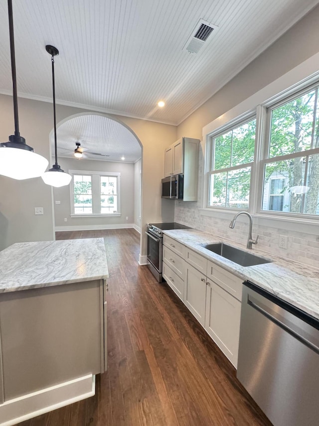kitchen with light stone countertops, appliances with stainless steel finishes, a sink, backsplash, and visible vents