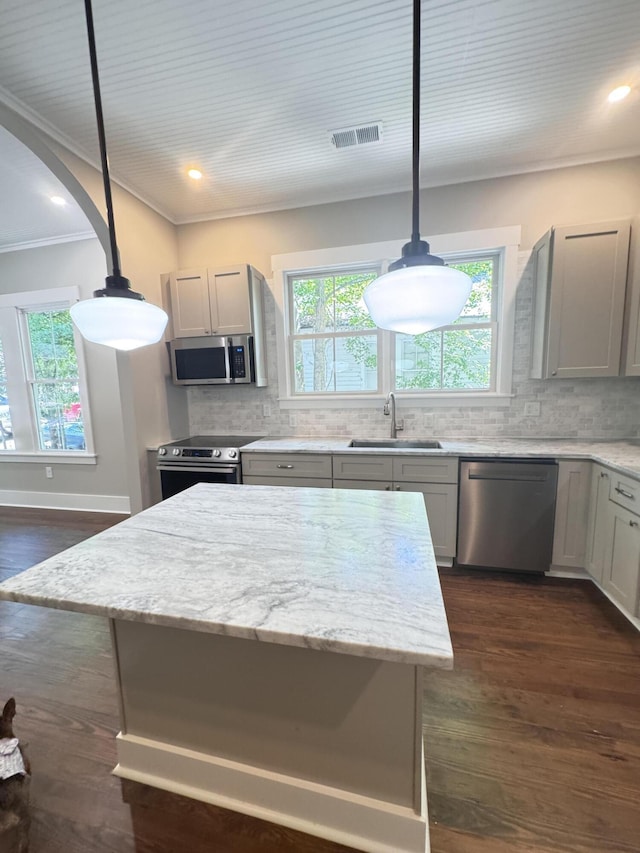 kitchen featuring decorative backsplash, appliances with stainless steel finishes, a sink, ornamental molding, and dark wood-type flooring