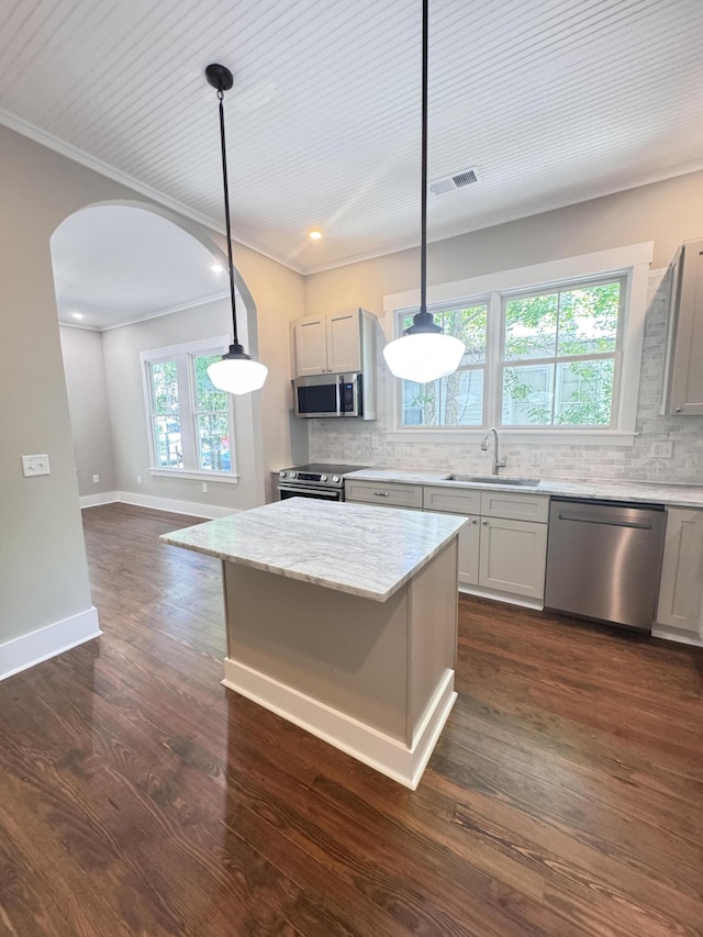 kitchen with visible vents, crown molding, appliances with stainless steel finishes, arched walkways, and a sink