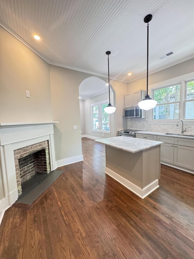 kitchen with visible vents, open floor plan, a sink, dark wood finished floors, and appliances with stainless steel finishes