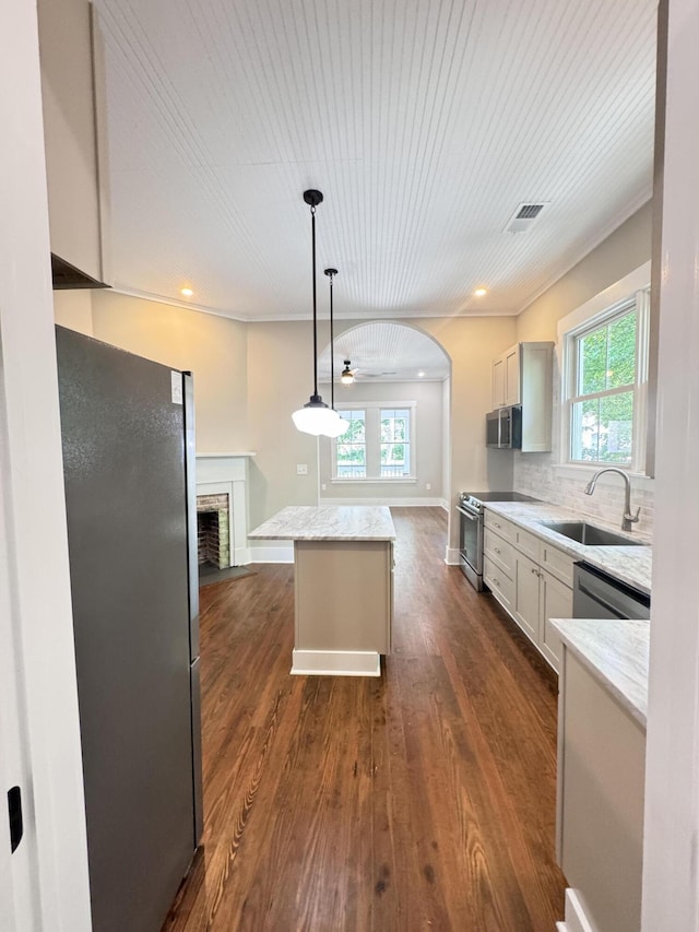 kitchen featuring a sink, stainless steel appliances, dark wood-type flooring, a kitchen island, and visible vents