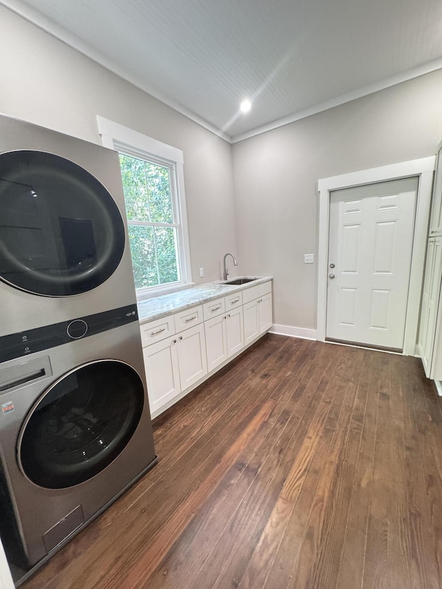laundry room featuring stacked washer / drying machine, dark wood finished floors, cabinet space, a sink, and recessed lighting