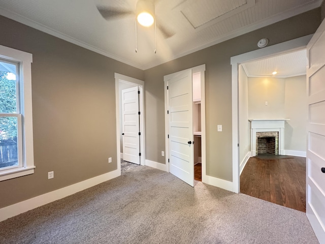unfurnished bedroom with crown molding, carpet flooring, baseboards, and a fireplace