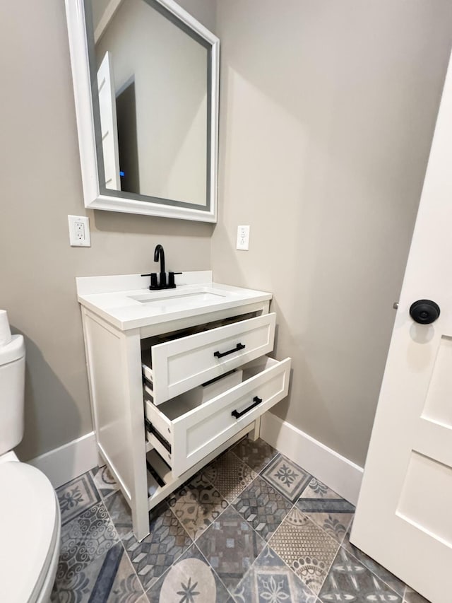 bathroom featuring baseboards, tile patterned flooring, toilet, and vanity