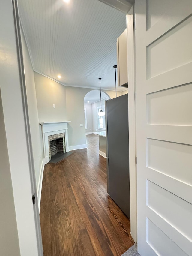 unfurnished living room with a fireplace, baseboards, recessed lighting, arched walkways, and dark wood finished floors