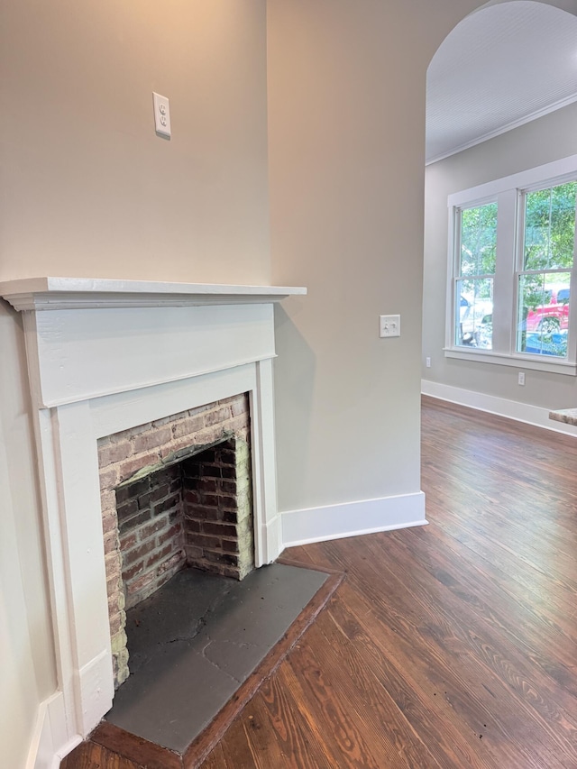 interior details with arched walkways, a fireplace, wood finished floors, baseboards, and ornamental molding