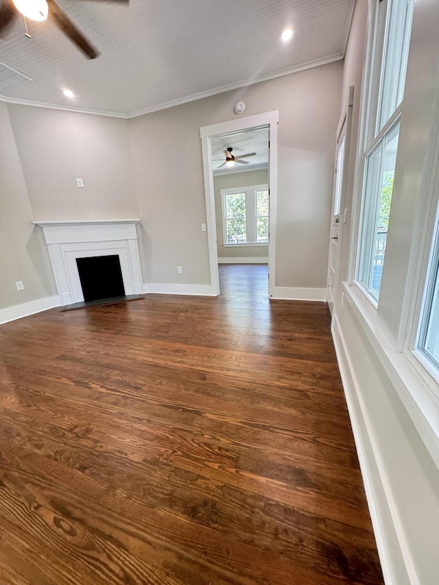 unfurnished living room featuring a ceiling fan, dark wood-style flooring, crown molding, a fireplace with flush hearth, and baseboards