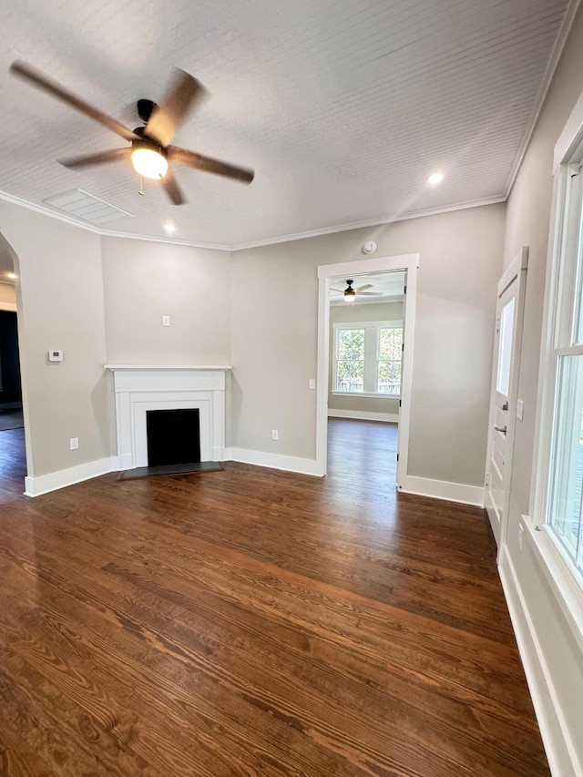 unfurnished living room with a fireplace with flush hearth, arched walkways, ornamental molding, and a ceiling fan