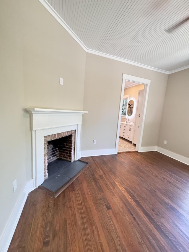 unfurnished living room with crown molding, a fireplace with raised hearth, baseboards, and wood finished floors