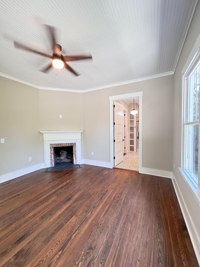 unfurnished living room with a ceiling fan, crown molding, a brick fireplace, baseboards, and dark wood-type flooring