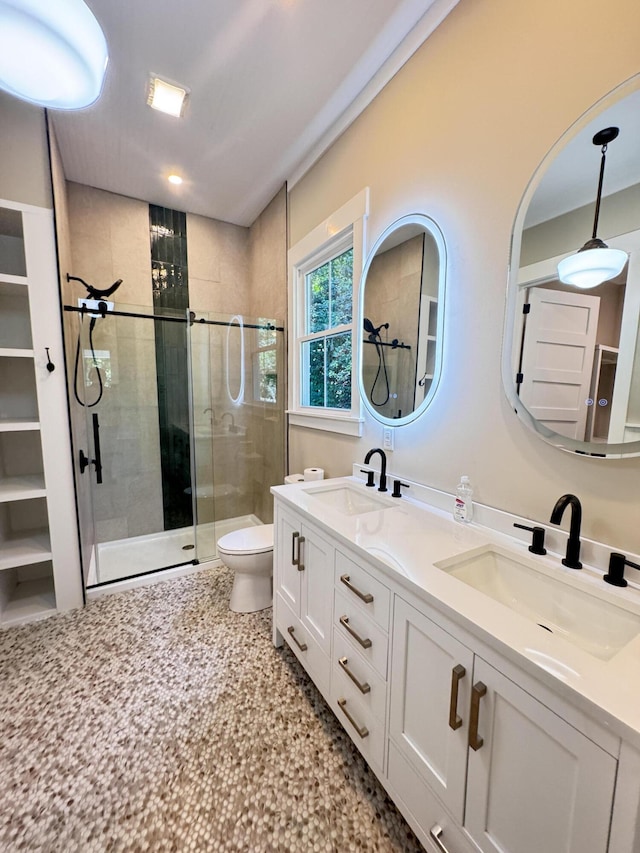 full bath featuring double vanity, toilet, a shower stall, and a sink