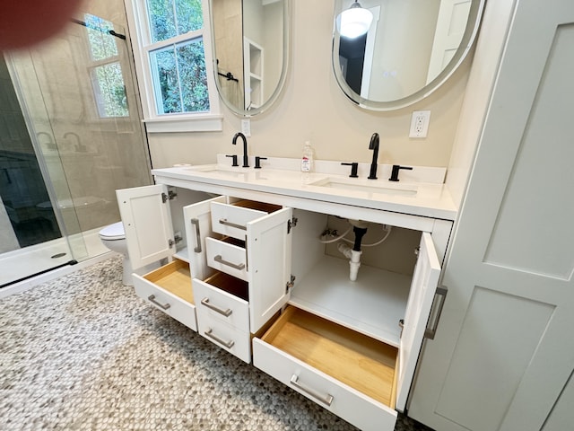full bath with a sink, a shower stall, toilet, and double vanity