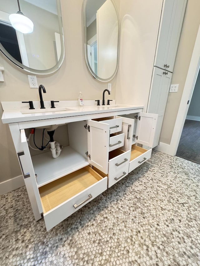 bathroom with a sink, baseboards, and double vanity