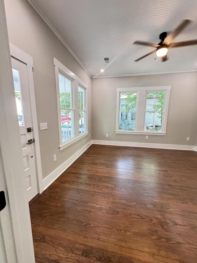 empty room featuring visible vents, ornamental molding, ceiling fan, and dark wood-style floors