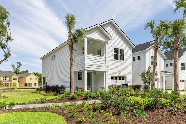 view of front of home with an attached garage, a balcony, a ceiling fan, a front lawn, and board and batten siding