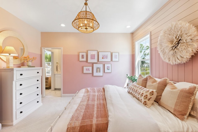 bedroom featuring wooden walls, connected bathroom, light colored carpet, a notable chandelier, and recessed lighting