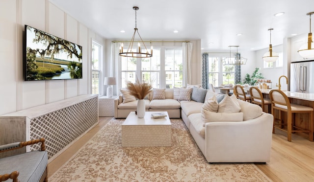 living area with recessed lighting, light wood-style flooring, and an inviting chandelier