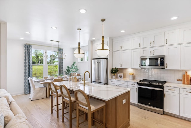 kitchen with light wood-style floors, tasteful backsplash, appliances with stainless steel finishes, and white cabinets