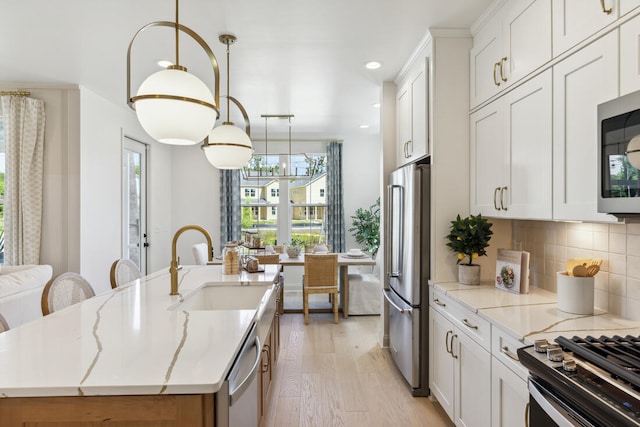 kitchen featuring a healthy amount of sunlight, light wood finished floors, appliances with stainless steel finishes, and a sink