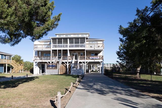 beach home with a sunroom, a front lawn, and a carport