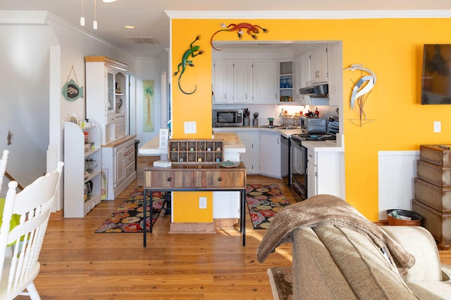 kitchen with white cabinets, black range, crown molding, light wood-type flooring, and a kitchen island