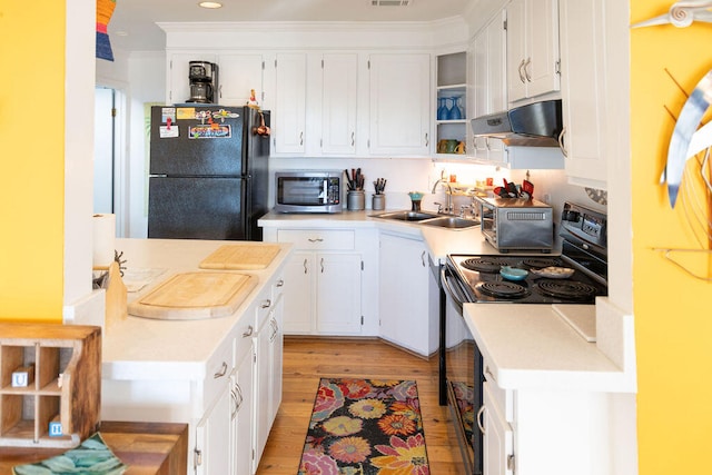 kitchen with black appliances, white cabinetry, sink, and light hardwood / wood-style flooring