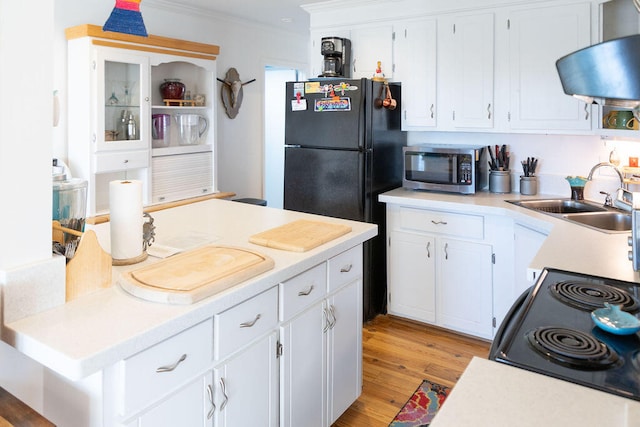 kitchen with white cabinetry, sink, light hardwood / wood-style flooring, crown molding, and black appliances