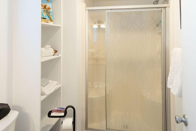 bathroom featuring a shower with door and toilet