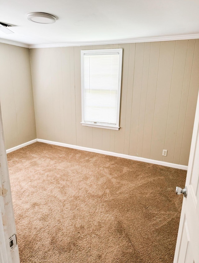 empty room featuring ornamental molding, carpet flooring, and wood walls